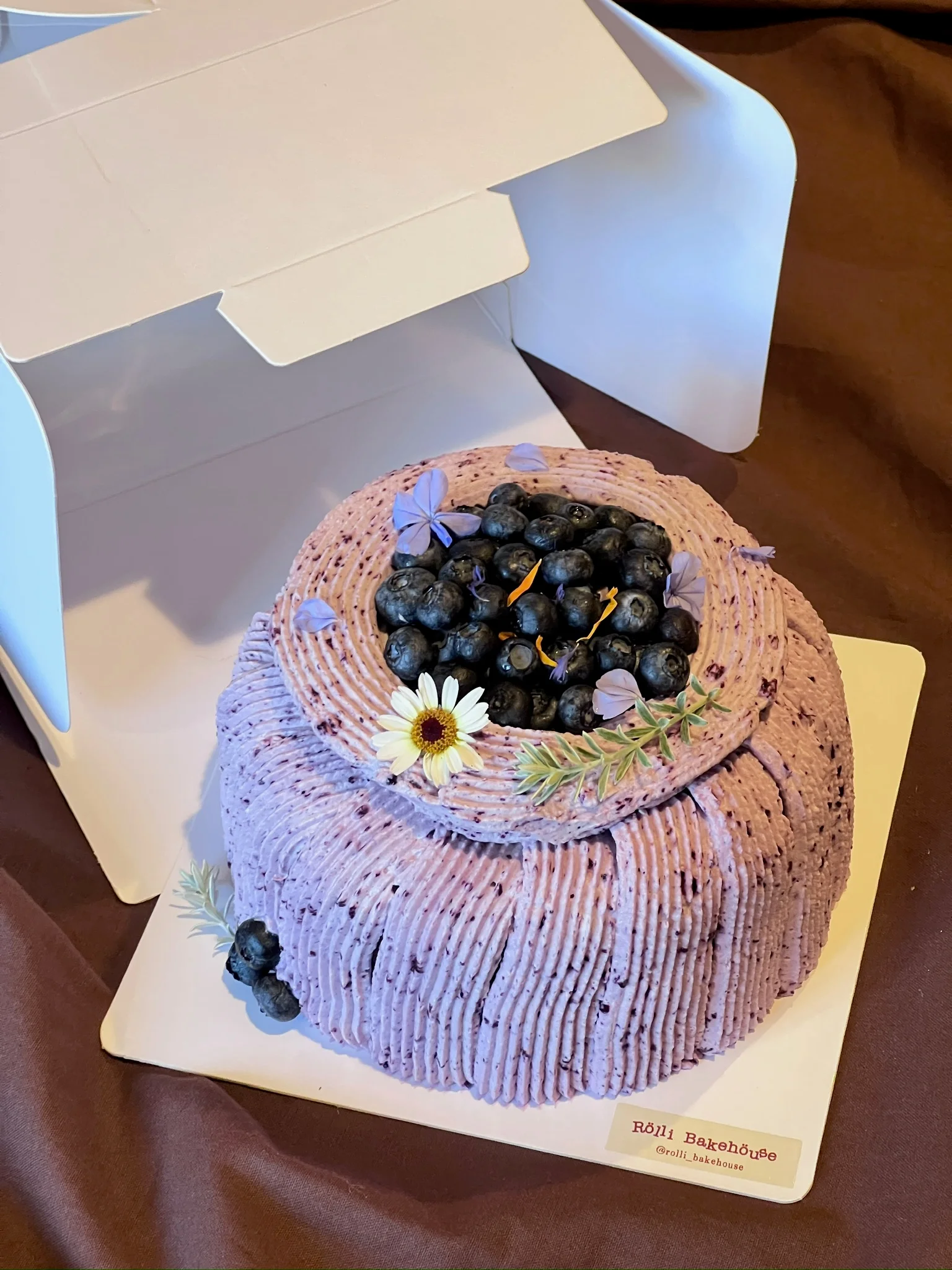 Purple frosted cake topped with blueberries and flowers