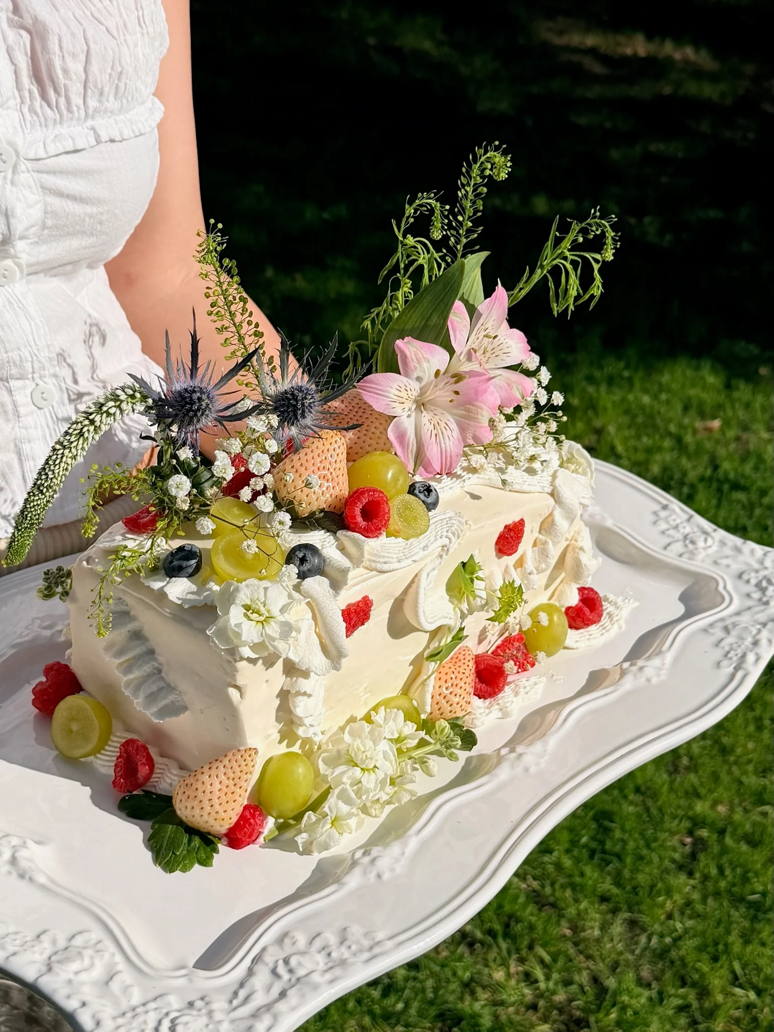 Cake decorated with fresh fruit and flowers on a garden table