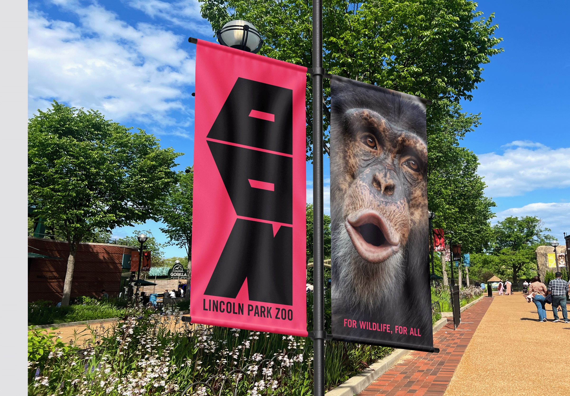 Pink ZOO banner and monkey banner on a lamppost along a park path